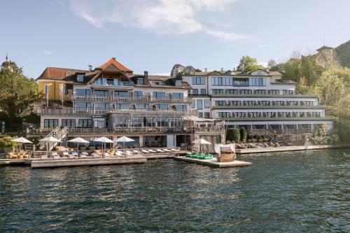 a hotel on the water with chairs and umbrellas at Das Traunsee - Das Hotel zum See 4 Stern Superior in Traunkirchen