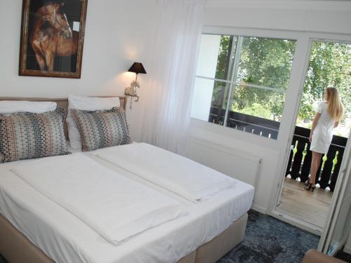 a bedroom with a bed and a woman looking out the window at Das Haus am See in Sinzheim