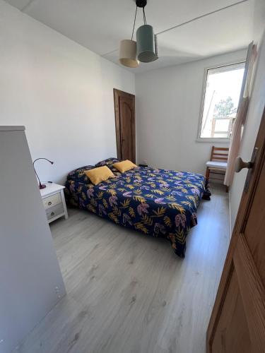 une chambre avec un lit avec une couverture bleue et une fenêtre dans l'établissement La Brémontine, à Parentis-en-Born