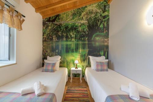 two beds in a room with a painting on the wall at Herdade Vale de Gaios in Odemira