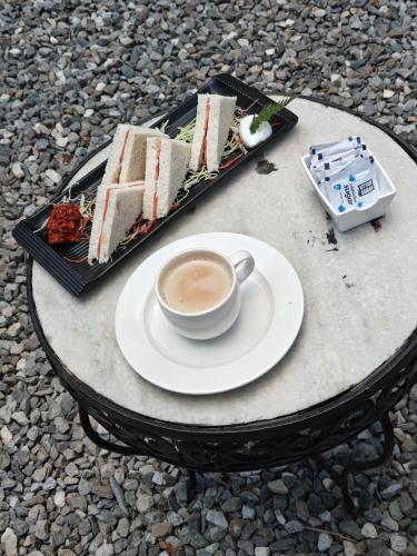 a cup of coffee and a plate of cake on a table at Treetop Glamps in Mussoorie