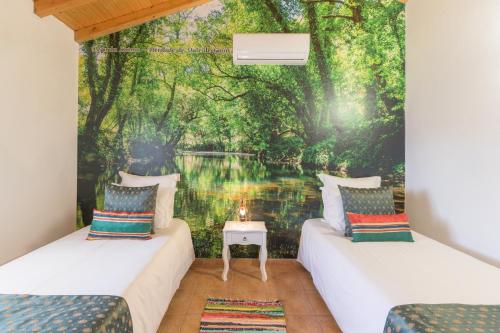 two beds in a room with a forest mural at Herdade Vale de Gaios in Odemira
