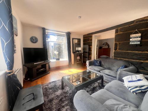 a living room with two couches and a tv at Apartment Porthmadog harbourside fantastic estuary views Great spot with parking in Porthmadog