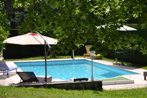 - une piscine avec un parasol et une chaise dans l'établissement Grand Cottage, à Mazeyrat-d'Allier