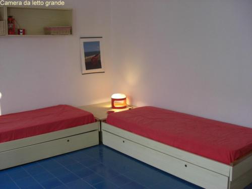 two beds with red sheets in a room at Casetta nel Villaggio Conca Specchiulla in Conca Specchiulla