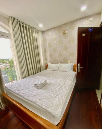 a bedroom with a bed with white sheets and a window at Gia Minh Hotel in Ho Chi Minh City