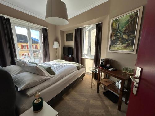 a bedroom with a bed and a table and windows at Boutique Centrale in Brione sopra Minusio