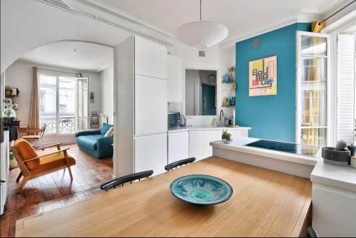 un salon avec une table et un mur bleu dans l'établissement superbe appartement place république, à Paris