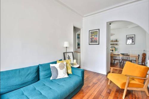 un salon avec un canapé bleu et une salle à manger dans l'établissement superbe appartement place république, à Paris