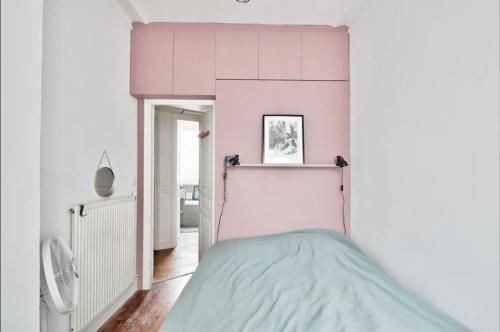 - une chambre rose et blanche avec un lit dans l'établissement superbe appartement place république, à Paris