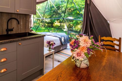 a kitchen with a table with a vase of flowers on it at Woodland dome in Thornbury