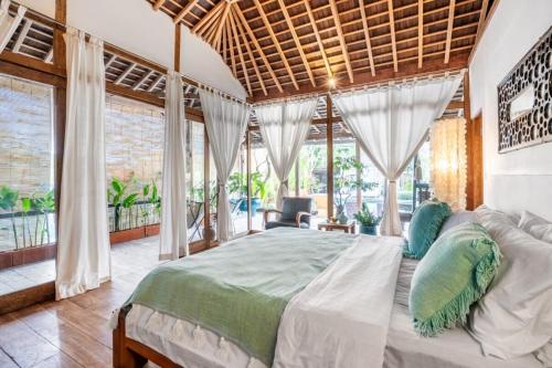 a bedroom with a large bed and large windows at Modern Joglo Villas in Canggu 5 Bedrooms in Kerobokan