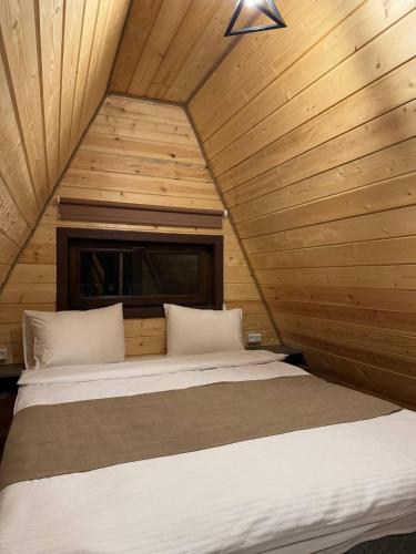 a bed in a room with a wooden wall at Karapetyans Guest House in Stepʼanavan