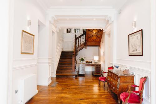 a hallway with a staircase in a home with white walls at Hôtel Château de la Marlière in Fourmies