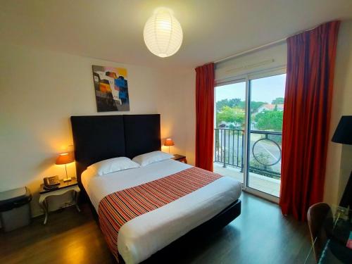 a bedroom with a bed and a large window at Adonis La Baule in La Baule