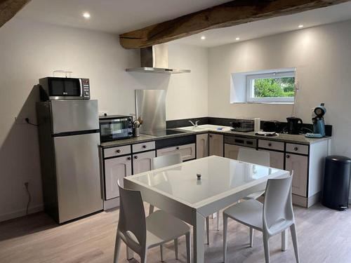 une cuisine avec une table blanche et des chaises dans l'établissement Lestable du pin, à Le Pin