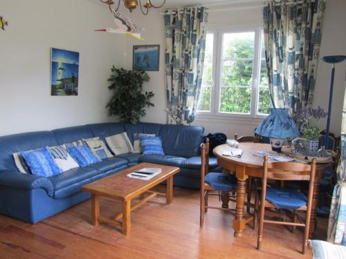 un salon avec un canapé bleu et une table dans l'établissement Maison Familiale Proche mer, à Ouistreham