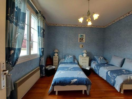 deux lits dans une chambre aux murs bleus dans l'établissement Maison Familiale Proche mer, à Ouistreham