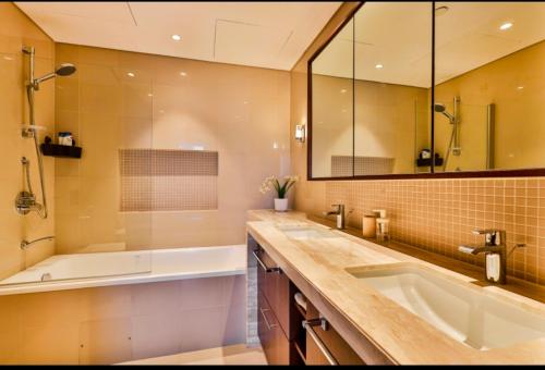 a bathroom with a tub and a sink and a mirror at " Luxury Stay in Downtown Dubai - Stunning Views & Prime location ! in Dubai