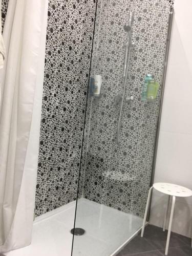a shower with a glass door and a stool at NEW Apartment with sunset views and pool in Żebbuġ