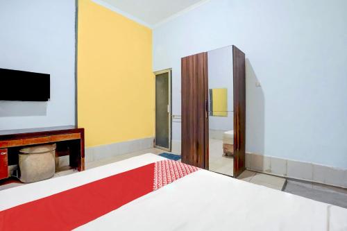 a bedroom with a bed and a tv on the wall at Hotel O Tegalsari Near Tunjungan Plaza in Surabaya