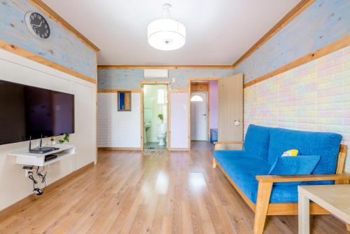 a living room with a blue couch and a tv at gochang sunonsan pungyeongpension in Gochang 