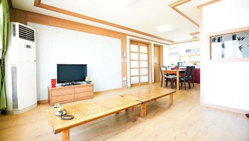 a living room with a tv and a wooden bench at Ulsan Lighthouse Pension in Ulsan