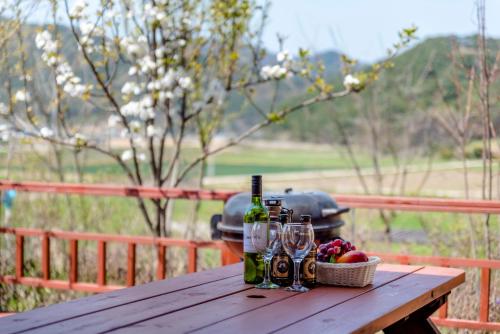 a picnic table with wine bottles and a basket of fruit at gochang sunonsan pungyeongpension in Gochang 