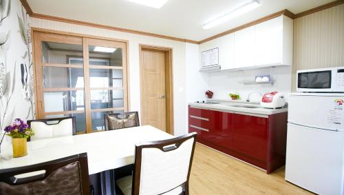 a kitchen with a white refrigerator and a table with chairs at Ulsan Lighthouse Pension in Ulsan