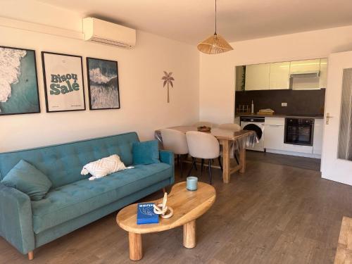 un salon avec un canapé bleu et une table dans l'établissement L'escapade salée - Saint Aygulf, à Fréjus