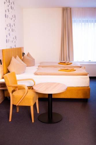 a bedroom with a bed with a table and a chair at Waldhotel in Boizenburg