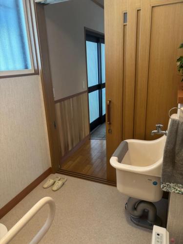 a bathroom with a toilet and a sink and a door at 安曇野温泉おもいやりの湯 in Azumino