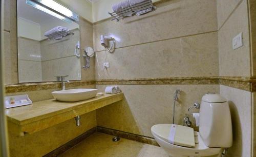 a bathroom with a sink and a toilet and a mirror at Hotel Southgate Delhi in New Delhi