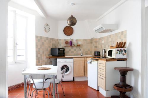 une cuisine avec une table et un appareil blanc dans l'établissement Chez Fred & Aldo Banyuls sur Mer, à Banyuls-sur-Mer