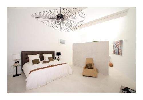 - une chambre blanche avec un lit et un ventilateur dans l'établissement Mas Chansonnet Gites et Chambres d'hotes de charme, à Les Fumades-Les Bains