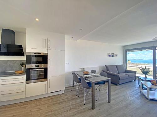 a kitchen and living room with a table and a couch at Spacieux studio terrasse, mer à 700m commerces, parking privé, Wi-Fi inclu - FR-1-349-116 in Larmor-Plage