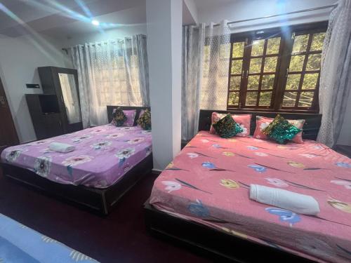 two beds in a bedroom with pink sheets and pillows at shalom inn home stay in Darjeeling