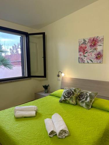 a bedroom with a green bed with two towels on it at Villa Relais ALGHERO -Country Villa with Pool in Alghero