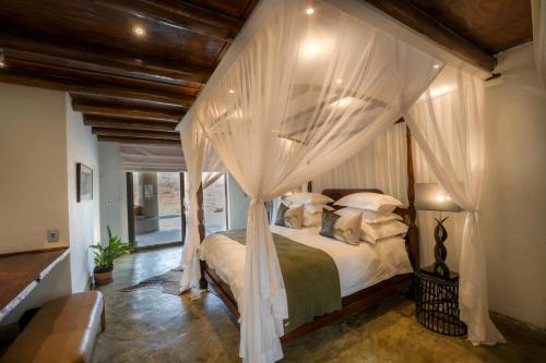 a bedroom with a canopy bed with white curtains at The Royal Madikwe Luxury Safari Lodge in Madikwe Game Reserve