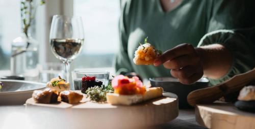 a person eating food on a table with a glass of wine at Lapland Hotels Pallas in Pallastunturi