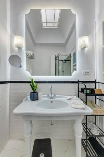 a white bathroom with a sink and a mirror at Palazzo Santa Maria - Historic Hotels of Europe in Ermoupoli