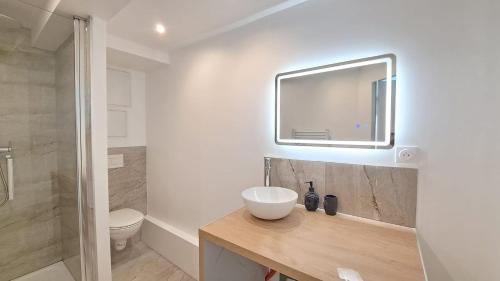 une salle de bain avec un lavabo, des toilettes et un miroir dans l'établissement Séville - Appartement agréable, à Reims