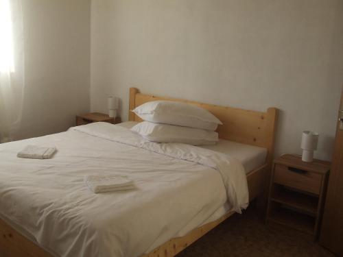 a bedroom with a bed with white sheets and pillows at Gentiana-Sureanu in Tău Bistra