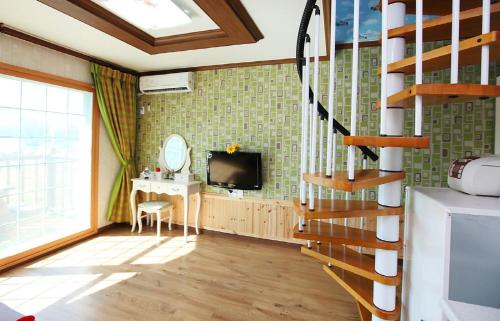a living room with a staircase and a television at Geojae Moraesoop Pension in Geoje 
