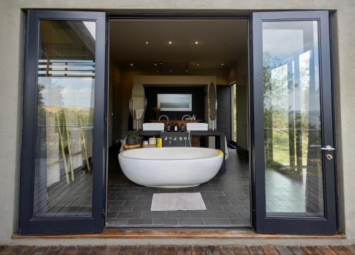 une grande baignoire dans une salle de bain avec des portes vitrées dans l'établissement Misverstand Boutique Farm Lodge, à Potchefstroom