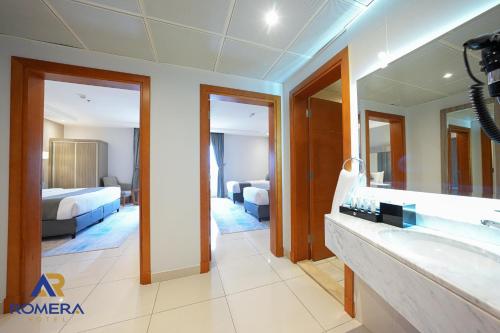 a bathroom with a tub and a sink and a bedroom at Romera Hotel in Jeddah