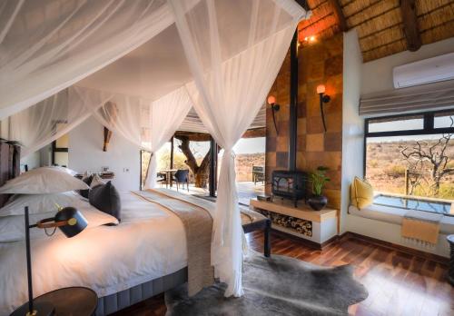 a bedroom with a large bed with white curtains at The Royal Madikwe Luxury Safari Lodge in Madikwe Game Reserve