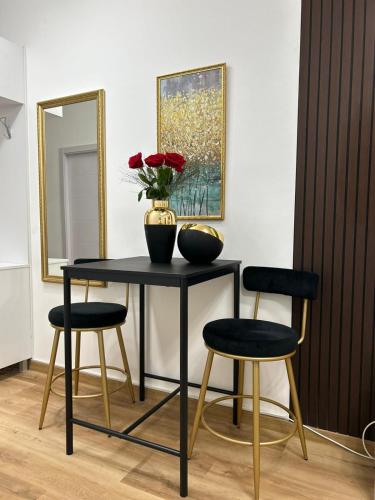 a table with two chairs and a vase with flowers on it at Relax In in Belgrade