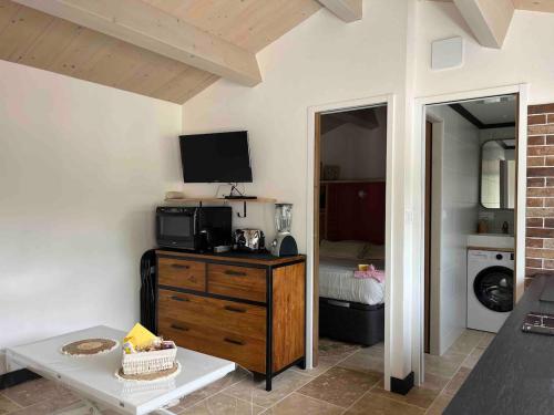 - un salon avec une télévision et une commode avec une chambre dotée d'un lit dans l'établissement Appartement neuf proche de la rochelle, à Puilboreau
