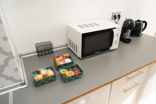 a kitchen counter with three baskets of food next to a microwave at Apartamentos Campo Del Príncipe in Granada